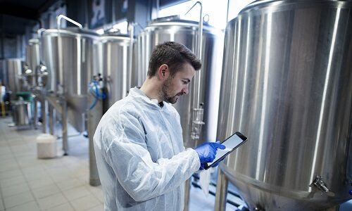 hombre tomando nota frente a unos tanques de color gris